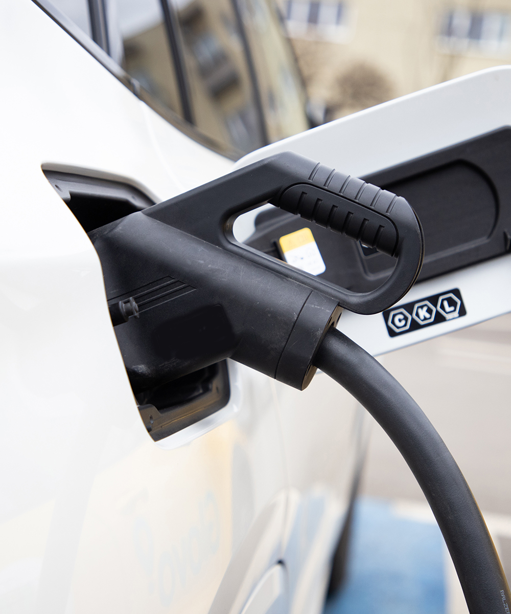 Un'auto elettrica bianca collegata a una stazione di ricarica rappresenta le soluzioni Noleggio Auto Elettriche, di mobilità elettrica e ibrida proposte da RentUp Novara per un noleggio a lungo termine più sostenibile.