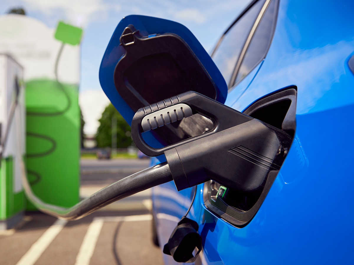 Un'auto elettrica collegata a una stazione di ricarica rappresenta le soluzioni di mobilità elettrica e ibrida proposte da RentUp Novara per un noleggio a lungo termine più sostenibile.
