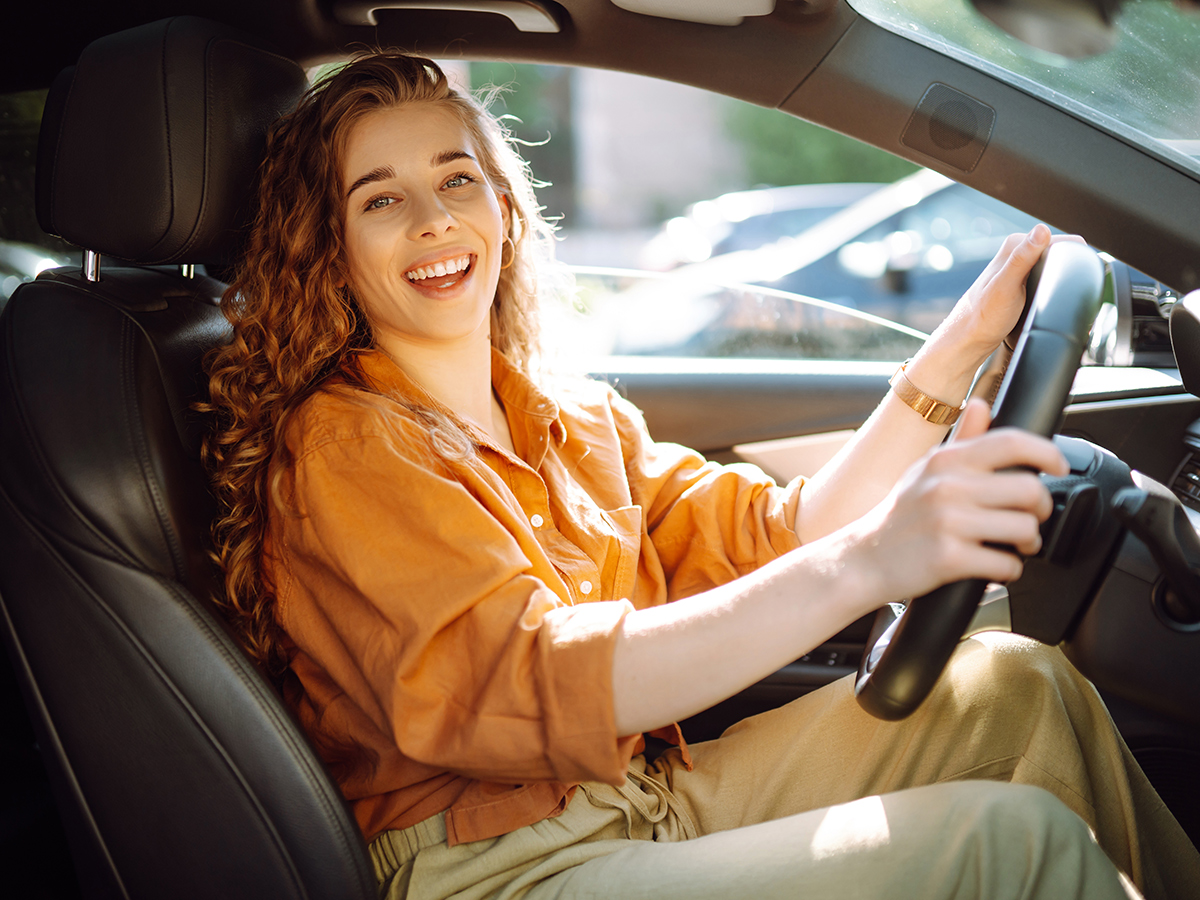 Cliente serena e sorridente alla guida della sua autovettura con il noleggio a lungo termine rentup novara